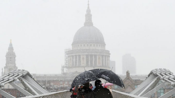 Người đi bộ trên chiếc cầu Thiên niên kỷ và phía xa là trung tâm London. Vùng trung tâm và phía Tây nước Anh đang hứng chịu đợt mưa tuyết lớn. Ở xứ Wales đợt mưa tuyết đạt kỷ lục với độ dày lên đến 30cm.
