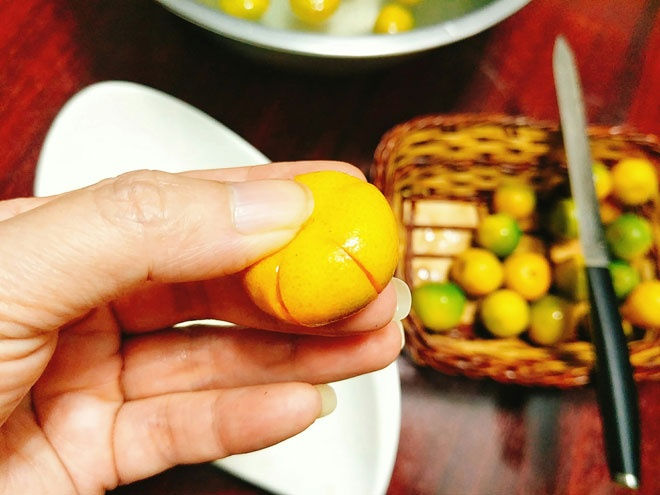 - Bước 3: Dùng dao sắc khứa 4 đường dọc trên quả quất tạo những khe nhỏ đều nhau, ấn dẹt cho ra hạt quất và loại bỏ bớt nước quất.   