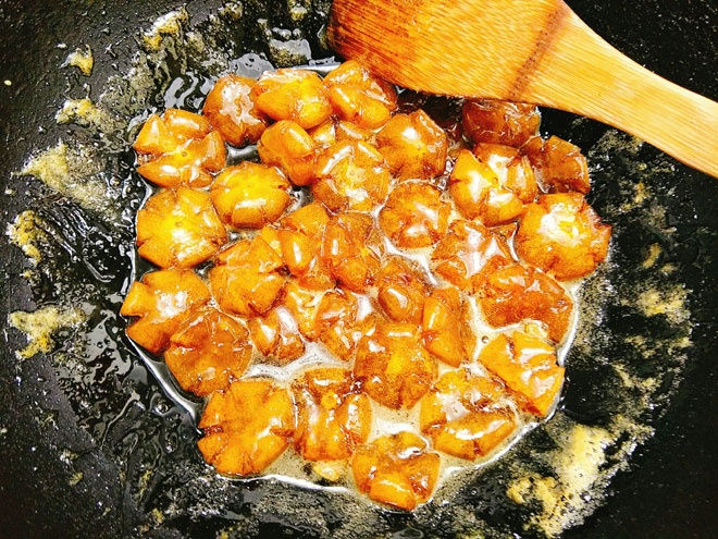 - Bước 6: Đổ quất và nước đường vào chảo rồi bật bếp nấu cho sôi, tiếp tục đun 5-7 phút nữa thì vặn lửa nhỏ hơn để mứt sôi lăn tăn và quất ngấm đường, thi thoảng bạn đảo đều. Khi thấy nước cạn dần và sánh lại, miếng mứt trong thì tắt bếp.   