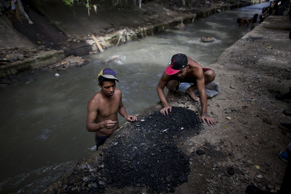   Hai người đàn ông đang phân loại các mảnh vụn mà họ kéo được đáy sông Guaire (Caracas, Venezuela) bị ô nhiễm để tìm kiếm vàng hoặc bất cứ thứ gì có giá trị. Venezuela đang chìm trong khủng hoảng khiến 30 triệu người phải vật lộn để tồn tại. Ảnh: Ariana Cubillos / AP  