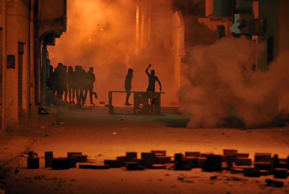   Người biểu tình ném đá vào lực lượng an ninh ở Tunis (Tunisia). Một người đã chết và hàng trăm người đã bị bắt trong các cuộc biểu tình bạo lực trên khắp Tunisia diễn ra trong tuần qua. Ảnh: EPA  