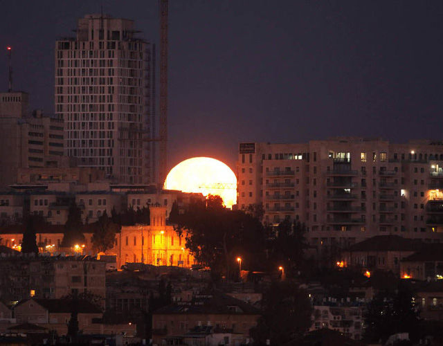 Mặt trăng như ngọn lửa sáng rực phía sau thành phố Jerusalem. Ảnh: AFP