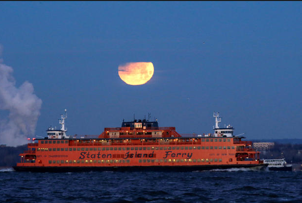   Mặt trăng xuất hiện phía sau chiếc phà Staten Island, được nhìn thấy ở Brooklyn, New York, ngày 31/1.  