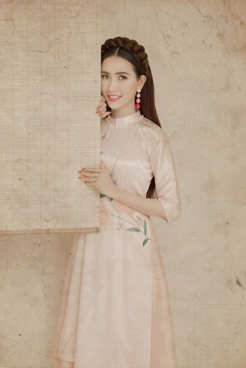 Với tà áo dài hồng phấn nhẹ nhàng, người đẹp thay đổi kiểu tóc sang cách tết bím, để xõa dài nữ tính.
