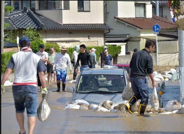 Cư dân đang ra sức dọn dẹp con đường sau khi nó trở thành một con sông do lũ lụt ở quận Aki, thành phố Hiroshima hôm 10/7/2018.  