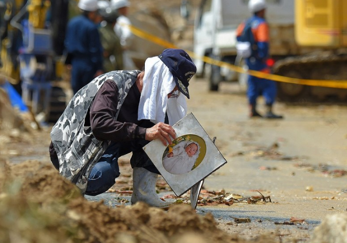 Một người đàn ông đang cố gắng tìm kiếm tài sản bị nhấn chìm trong bùn ở thị trấn Kumano, tỉnh Hiroshima hôm 9/7/2018.  