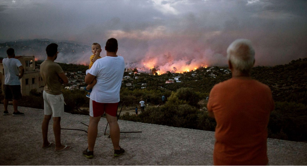   Mọi người xuôi tay đứng nhìn ngọn lửa tàn phá trong vô vọng ở thị trấn Rafina, gần Athens, Hy Lạp.  