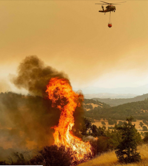   Một máy bay trực thăng chuẩn bị thả nước để dập tắt đám cháy.  