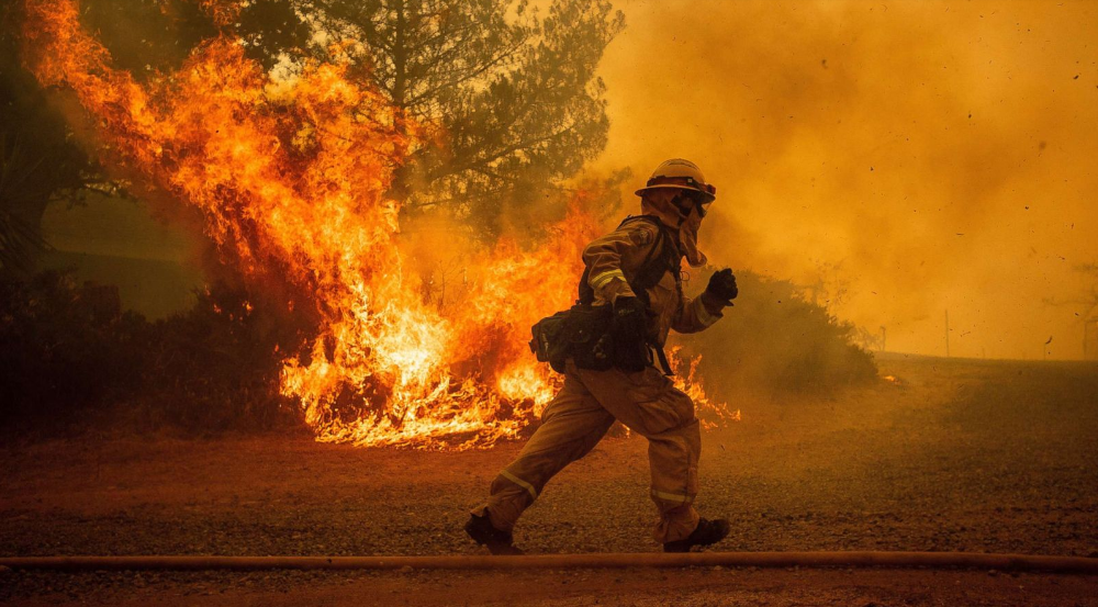   Anh lính cứu hỏa này chạy đang ra sức để cứu ngôi nhà chìm trong lửa.  