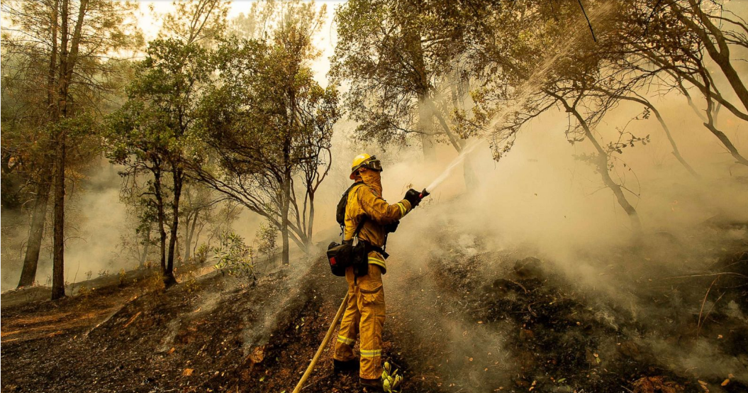   Lính cứu hỏa đang phun nước vào đám cháy ở Redding, California.  