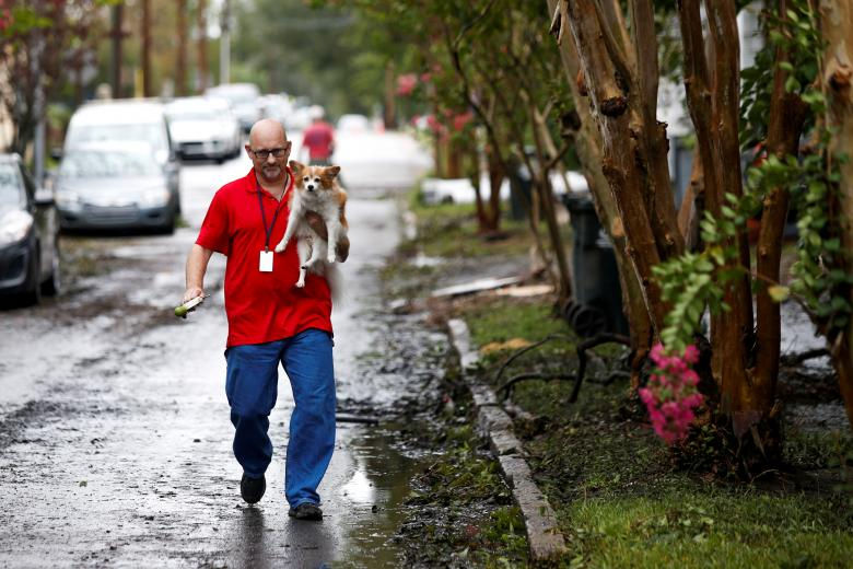   Người đàn ông ẳm người bạn của ông trở về nhà sau khi bão Florence đi qua. Ảnh: Reuters  