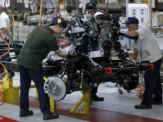 Công nhân lắp đặt động cơ cho xe hơi tại nhà máy lắp ráp ô tô BAIC ORU của Trung Quốc ở Bắc Kinh.