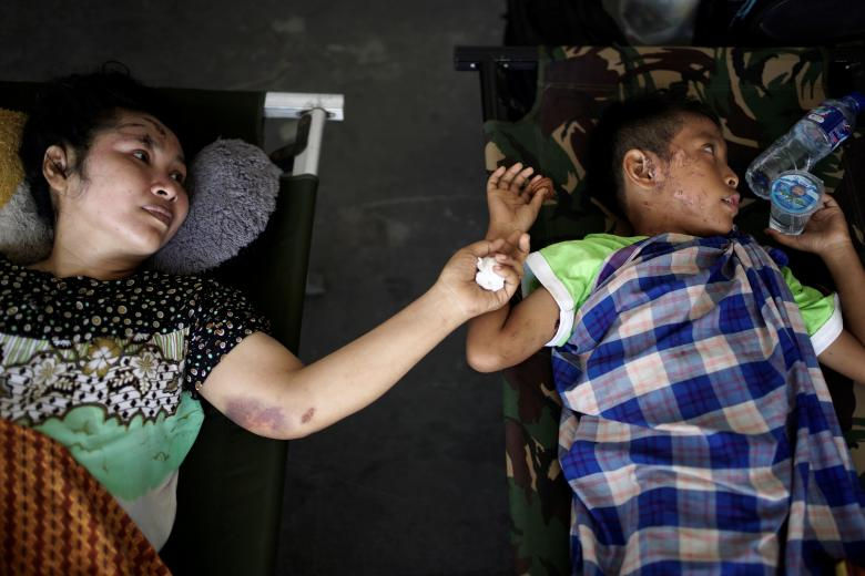   Hình ảnh hai mẹ con bị thương do động đất và sóng thần, họ phải nằm lực lượng cứu hộ đến để được đưa đến vùng an toàn. (Ảnh: Reuters)  