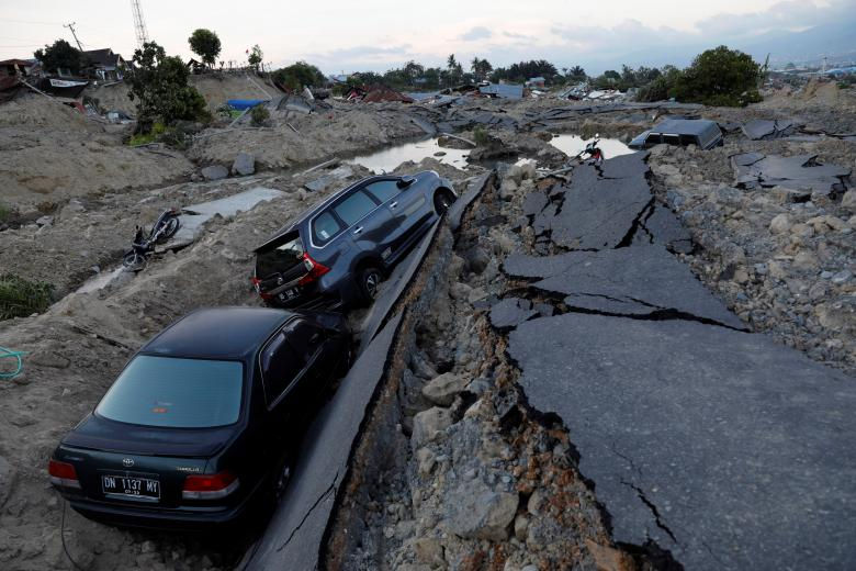   Hai chiếc xe hơi đang bị mắc kẹt sau khi trận động đất xảy đến huyện Balaroa ở Palu, đảo Sulawesi. (Ảnh: Reuters)  
