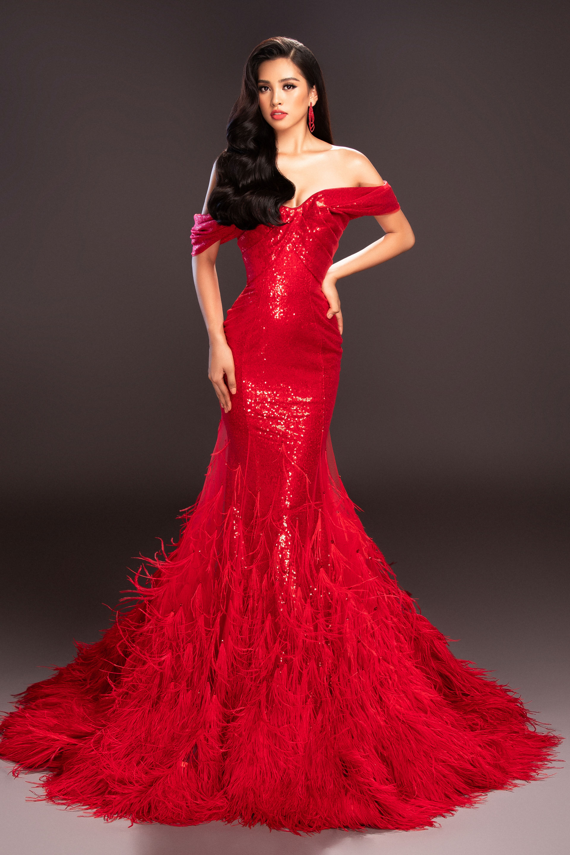  Màu đỏ của chiếc váy đính lông vũ phù hợp làn da của hoa hậu 18 tuổi.