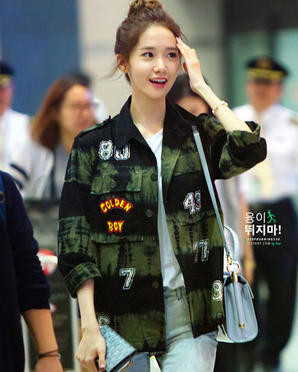 YoonA tươi tắn và trẻ trung tại sân bay với áo sơ mi quân đội ấn tượng khoác ngoài, kết hợp với áo phông trắn bên trong và quần jeans cùng ví và túi xách cùng màu.