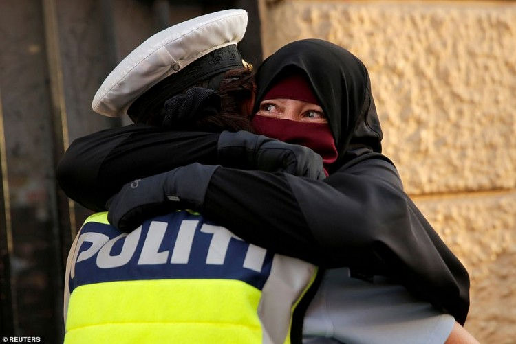 Ayah, 37 tuổi, một phụ nữ đeo mạng che mặt niqab, khóc khi cô được cảnh sát ôm trong một cuộc biểu tình phản đối lệnh cấm đeo mạng che mặt ở ngoài đường ở Copenhagen, Đan Mạch. (Ảnh chụp ngày 1/8/2018 bởi nhiếp ảnh gia Andrew Kelly)