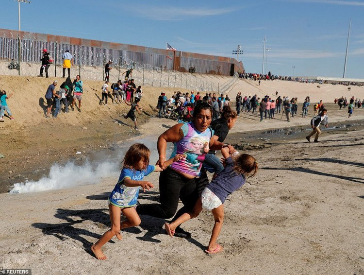 Cô Maria Meza nắm lấy cánh tay của hai cô con gái sinh đôi Cheili và Saira (5 tuổi) bỏ chạy khi cảnh sát ném đạn hơi cay cạnh hàng rào biên giới Mỹ - Mexico ở Tijuana, Mexico. (Ảnh chụp ngày 25/11/2018 bởi nhiếp ảnh gia của Kim Kyung-Hoon)