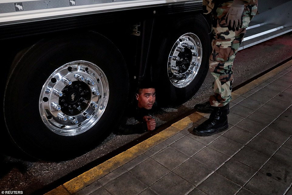 Một người di cư trốn dưới xe tải khi một cảnh sát đang đứng chờ để bắt anh ta tại cảng Patras, Hy Lạp ngày 8/3/2018. Patras là nơi những người di cư định bắt phà rời Hy Lạp để tới Italy.