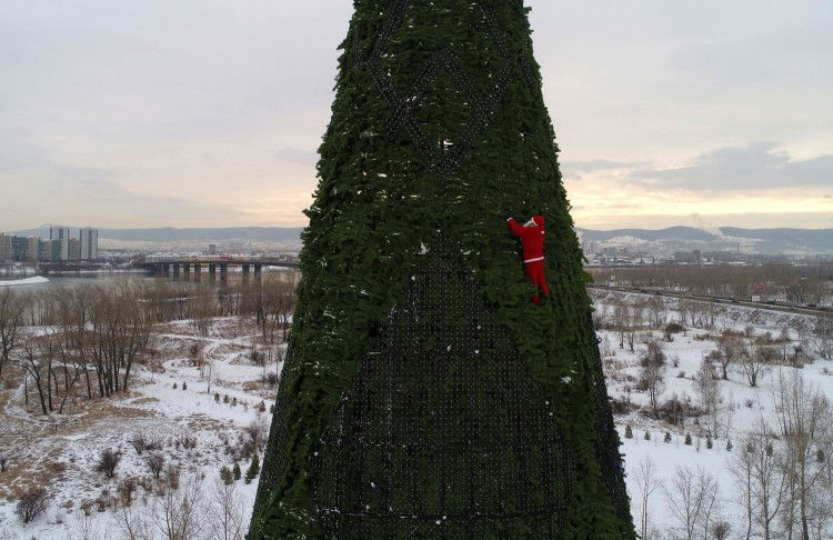 Một người đàn ông trong trang phục Ông già Tuyết đang trang trí cây thông Noel cao 57 m ở đảo Tatyshev trên sông Yenisei, thành phố Krasnoyarsk, Nga. Ảnh: Reuters