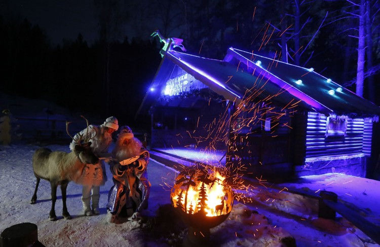Một người đàn ông mặc trang phục Father Frost (Ông già Tuyết tương tự như Santa Claus ở phương Tây) và người phụ nữ đóng vai cháu gái Snegurochka đang đứng gần đống lửa trong màn biểu diễn ở công viên Royev Ruchey, ngoại ô thành phố Krasnoyarsk của Nga ngày 12/12. Ảnh: Reuters