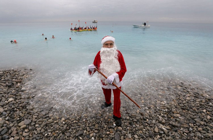 “Ông già Tuyết” đứng trên bờ trong khi nhiều người khác đang ở dưới nước. Họ đang có mặt ở một sự kiện bơi truyền thống dịp Giáng sinh ở sông Nice, Pháp ngày 16/12. Ảnh: Reuters