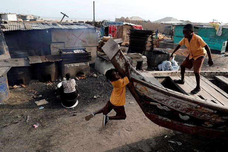  Các cậu bé vui chơi trong khi mẹ đang chuẩn bị món cá hun khói ở Jamestown, Accra, Ghana.