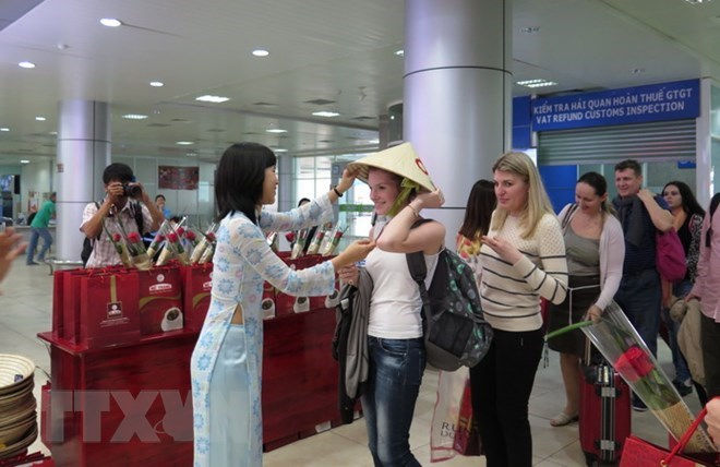 Các du khách Nga nhận món quà là chiếc nón lá Việt Nam. (Ảnh: Tiên Minh/TTXVN).