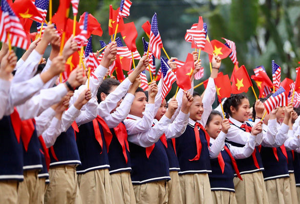 Các học sinh Việt Nam cầm cờ Việt Nam và Mỹ chào đón buổi hội đàm giữa Tổng bí thư-Chủ tịch nước Nguyễn Phú Trọng và Tổng thống Mỹ Donald Trump tại Phủ Chủ tịch.