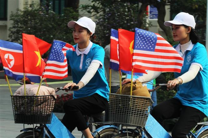 Thiếu nữ Việt Nam đạp xe diễu hành với cờ Việt Nam, Mỹ và Triều Tiên trên đường phố Đinh Tiên Hoàng, Hà Nội. Ảnh: TTXVN