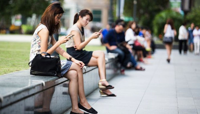Người dùng điện thoại di động trên đường phố ở quận kinh doanh trung tâm Singapore – Ảnh: Getty/CNBC.
