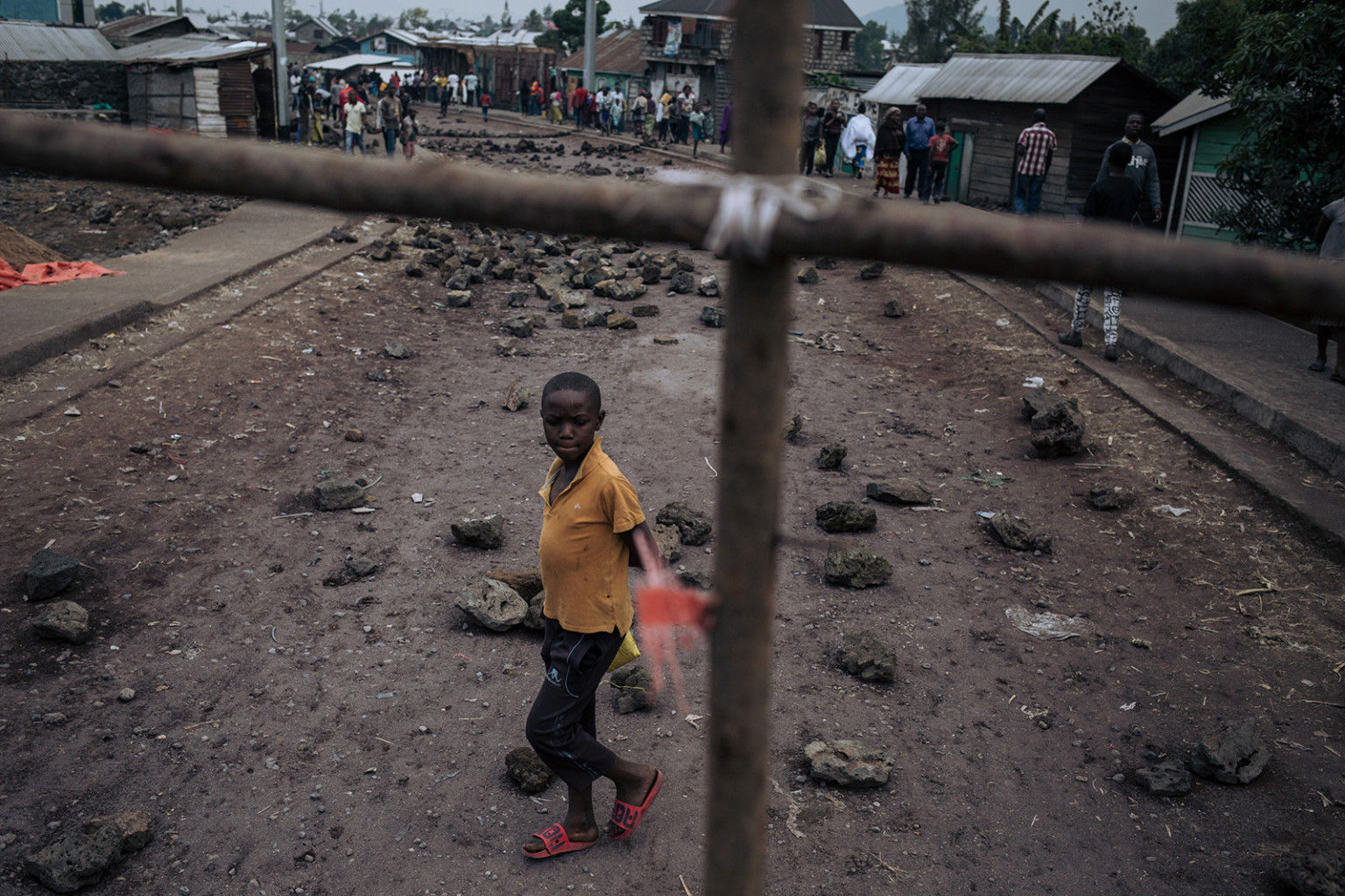   Một cậu bé vượt qua chướng ngại vật ở quận Kilijiwe phía bắc Goma ở miền đông Cộng hòa Dân chủ Congo vào ngày 24 tháng 7. Cư dân rào chắn đường, làm tê liệt mọi hoạt động để phản đối cái chết của bốn người, trong đó có hai thanh thiếu niên, bị giết bởi những tên cướp có vũ trang.  