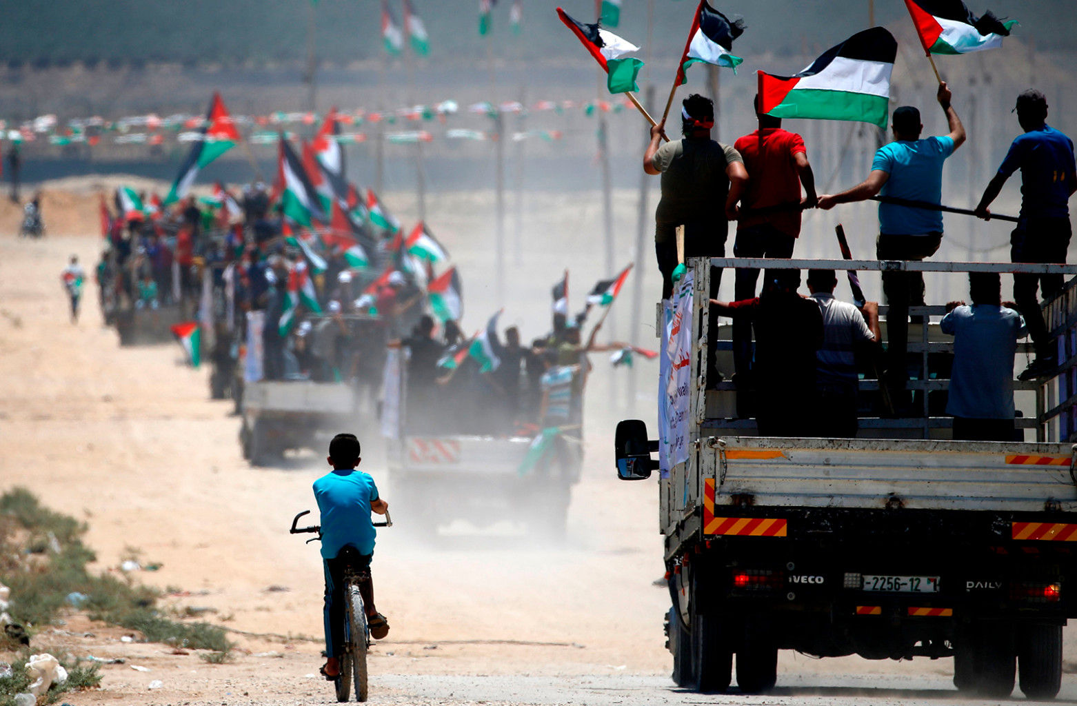   Người biểu tình Palestine vẫy cờ quốc gia khi họ lái xe về phía hàng rào biên giới với Israel, phía đông thành phố Gaza, vào ngày 22 tháng 7.  