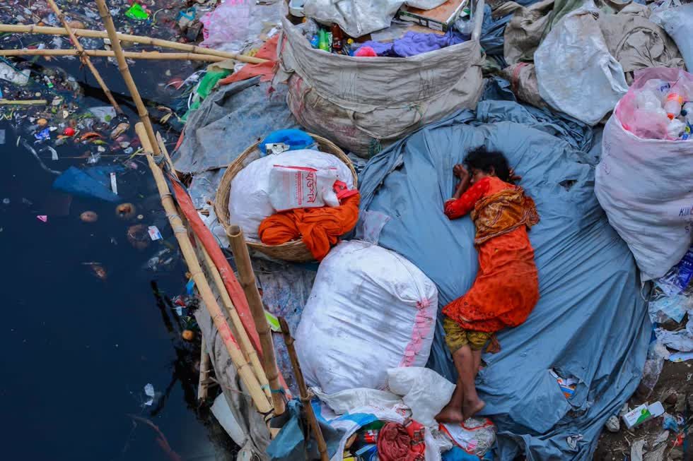 Một phụ nữ ngủ trên bờ sông ngập đầy rác ở Dhaka Bangladesh. Rác thải là nguồn nghiêm trọng gây ô nhiễm các dòng sông ở Nam Á. Ảnh: Amdad Hossain.