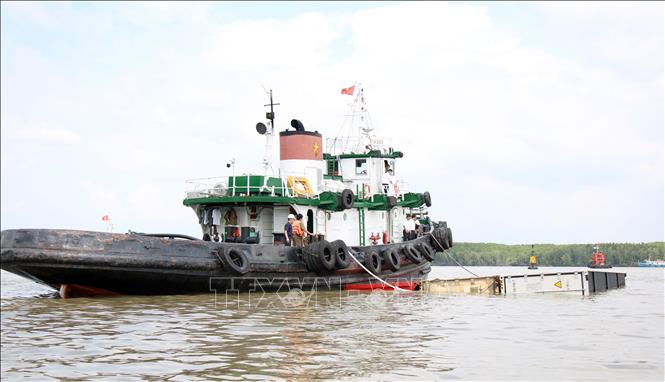 Các phương tiện lai dắt thùng container vào tập kết gần bờ, tạo thông thoáng cho lòng sông Lòng Tàu. Ảnh: TTXVN