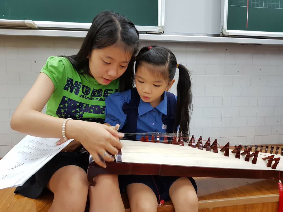 Thùy Trang dạy đàn cho các em nhỏ ở trường Hòa Bình - Ảnh: Cẩm Vien