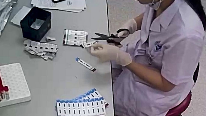   Hình ảnh nhân viên khoa Vi sinh Y học, BV Đa khoa Xanh Pôn cắt đôi que thử HIV, viêm gan B (ảnh cắt từ clip).  