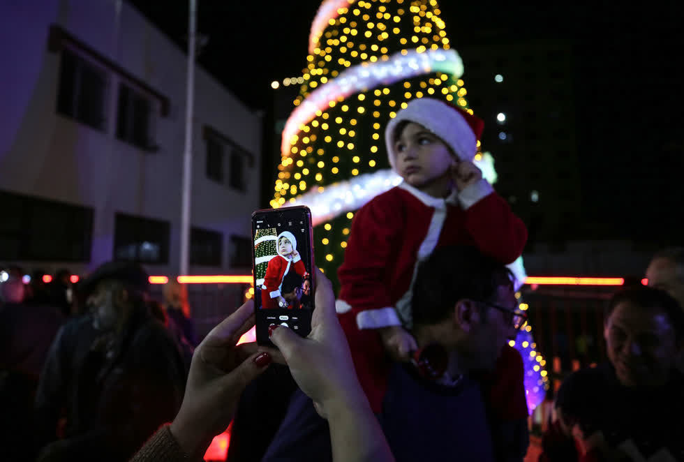 Một đứa trẻ trong trang phục ông già Noel được chụp ảnh khi mọi người tụ tập quanh một cây thông Giáng sinh được chiếu sáng ở thành phố Gaza, Gaza vào ngày 3/12. Ảnh: Getty.