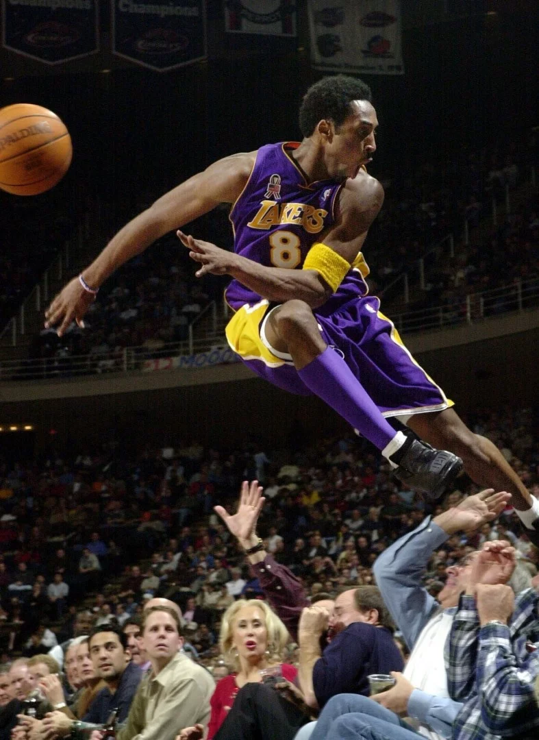 Ảnh chụp năm 2001, Kobe Bryan đã nhảy qua một hàng rào người ham mộ sau khi cứu bóng ra khỏi giới hạn trong trận cầu Laker 107-101 trước Houston Rockets ở Houston. Ảnh: AP.