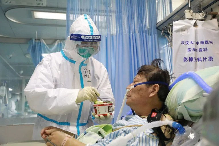 Y tá mặc đồ bảo hộ đang chăm sóc một bệnh nhân nhiễm virus corona tại khu cách ly của bệnh viện ở Vũ Hán. Ảnh: Reuters.