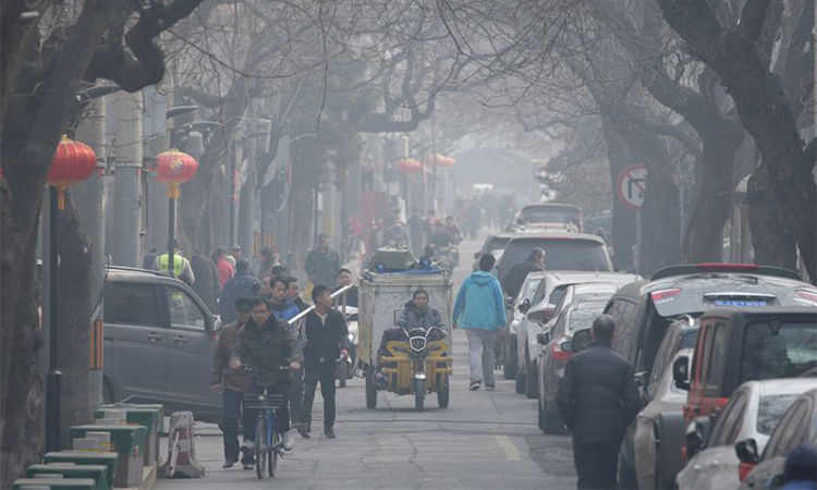 Người dân đi lại trong làn khói mù ô nhiễm tại một phố cổ ở Bắc Kinh.
