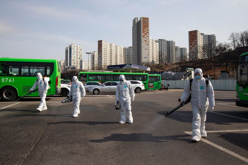 Công nhân mặc đồ bảo hộ phun thuốc khử trùng tại một kho xe buýt ở Seoul, ngày 24/2. Ảnh: Bloomberg.