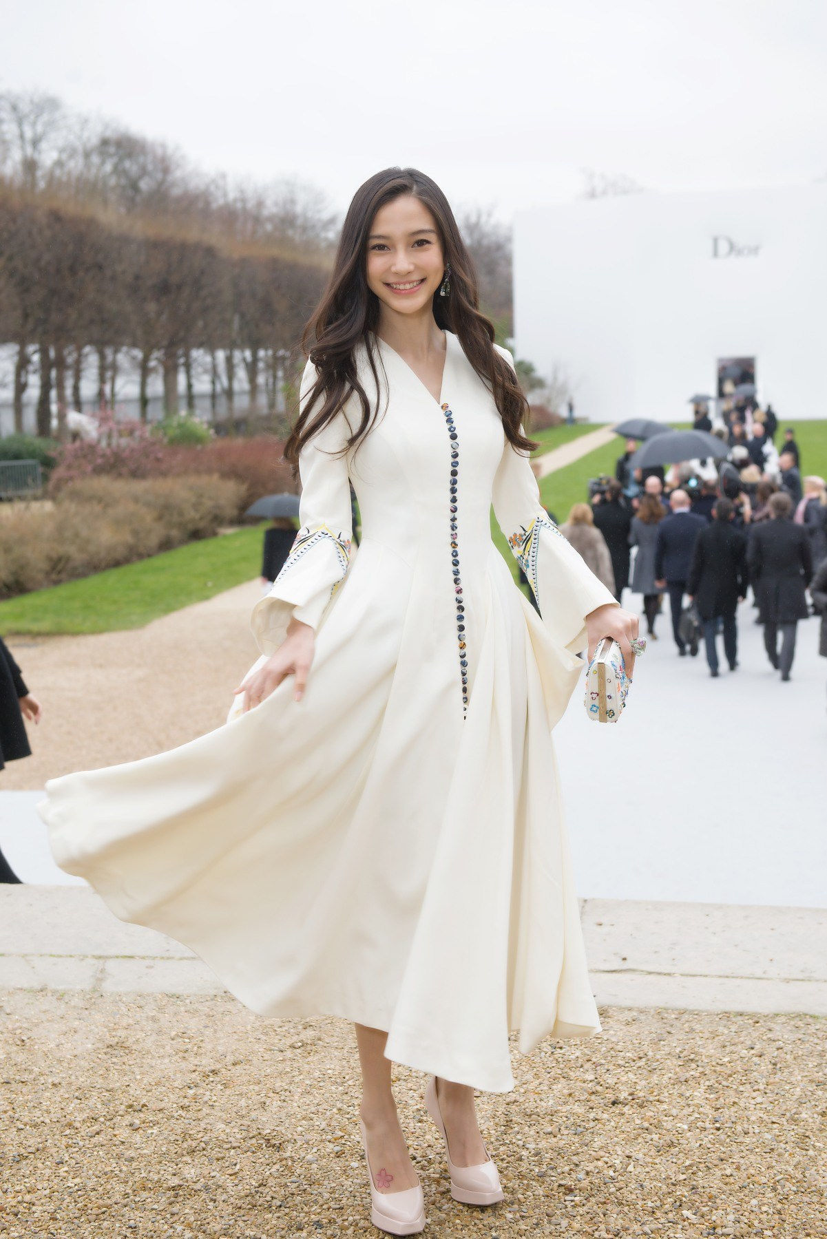   Bộ váy trắng cổ V với hàng cút màu sắc làm điểm nhấn là lựa chọn của Angelababy khi tham dự buổi trình diễn Dior Thu – Đông 2015. (Ảnh: Sina)   