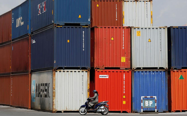   Một phụ nữ đi xe máy ngang qua các container tại cảng Hải Phòng vào ngày 25/9/2018. Ảnh: REUTERS.  