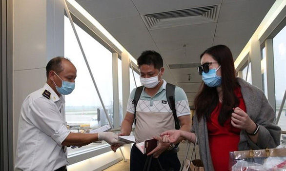  Nhân viên y tế kiểm tra phiếu khai báo y tế của hành khách trước khi làm thủ tục nhập cảnh tại cửa khẩu sân bay quốc tế Nội Bài - Ảnh: TTXVN 