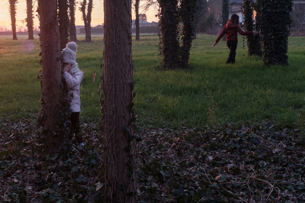   Bianca trốn sau một gốc cây khi cô bé chơi với mẹ trong một công viên trống vắng vào ngày 23/2. Ảnh: Reuters.  