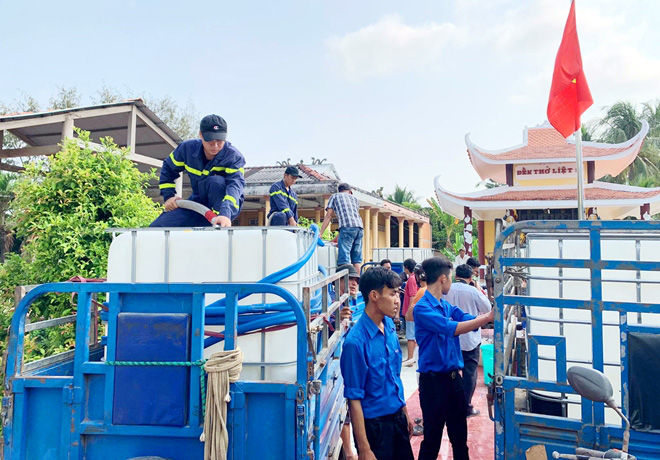 Cán bộ, chiến sĩ Phòng Cảnh sát PCCC&CNCH phối hợp cùng đoàn viên thanh niên dùng xe kéo để vận chuyển nước ngọt đến các hộ dân ở xa.