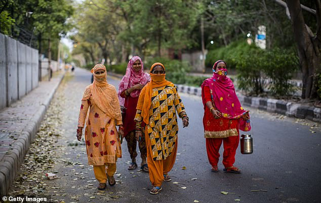 Một nhóm phụ nữ mang theo vật dụng để mua sữa khi họ đi trên con đường vắng ở New Delhi.