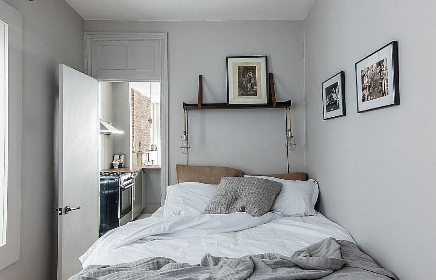 Phòng ngủ đơn sắc với không gian hạn chế và những bức ảnh đen trắng trên tường.