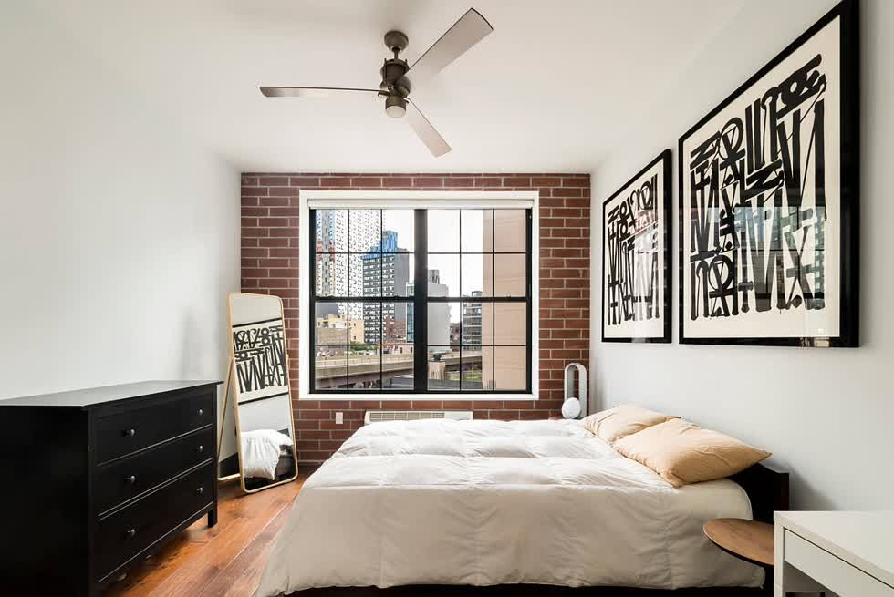 Phòng ngủ Glam NYC màu trắng với tác phẩm nghệ thuật khung sang trọng và tường gạch giả.